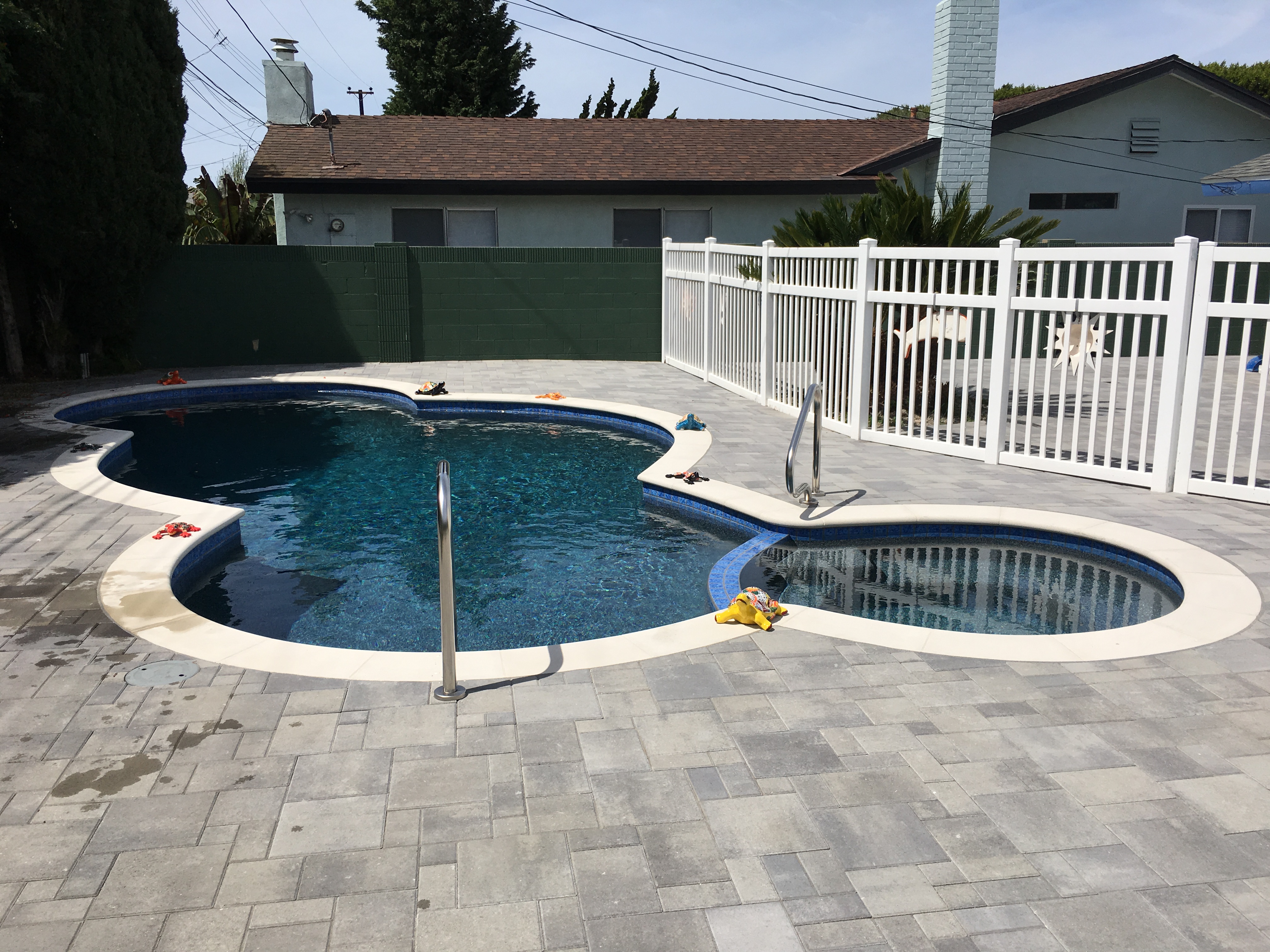 Gray pavers with white coping and pebble finish