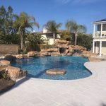 pool with rockwork, slide and grotto, baja bench and white pavers